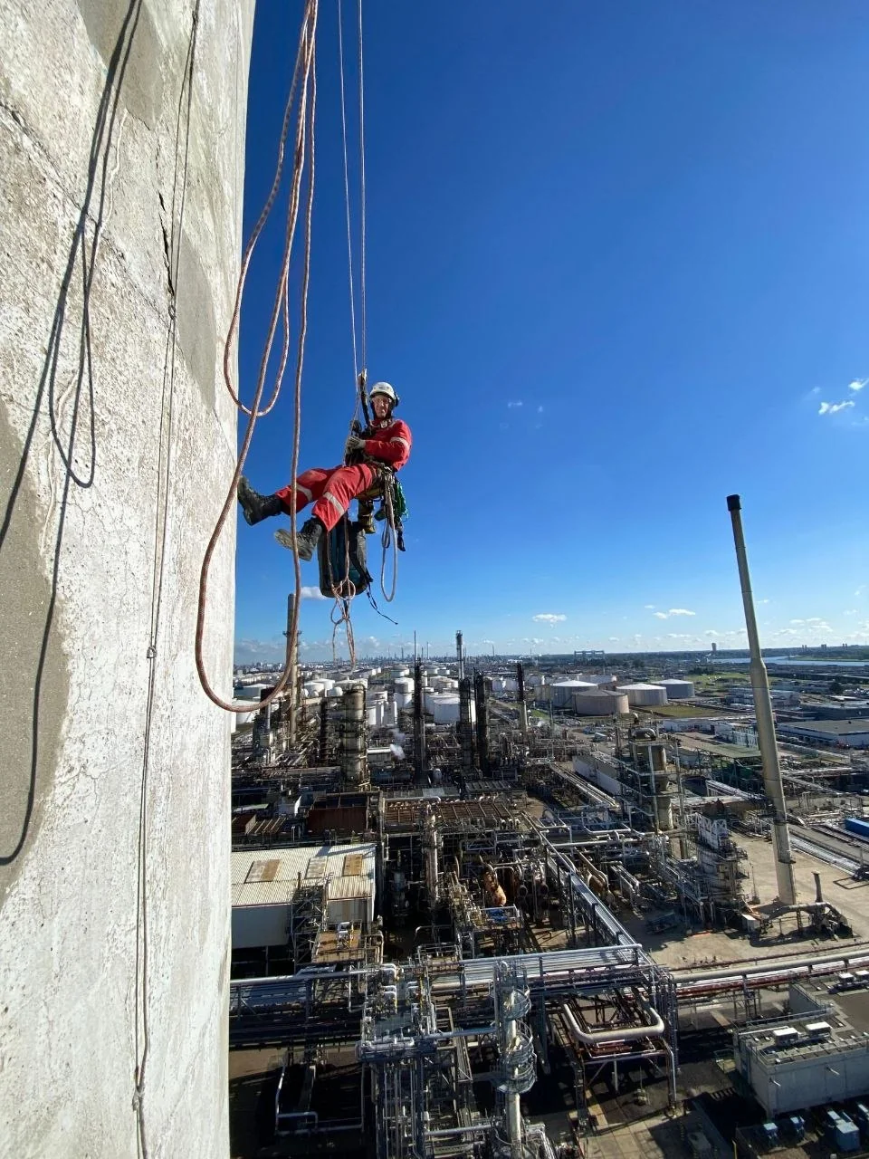 Alpinist utilitar lucrează pe fațada unui obiect industrial
